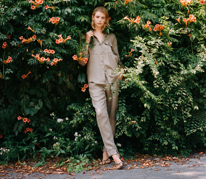 Woman standing in front of a green bush with orange flowers